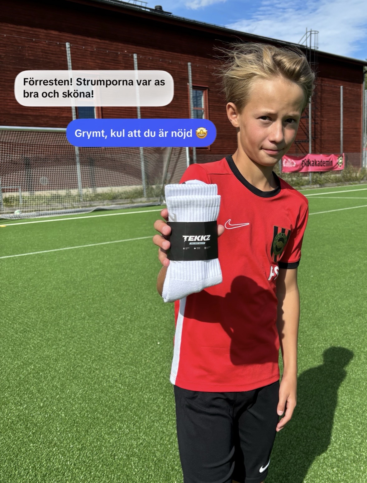 Ung spelare i röd matchtröja håller upp ett par TEKKZ Pro Grip Socks i förpackning – "Förresten! Strumporna var as bra och sköna!"